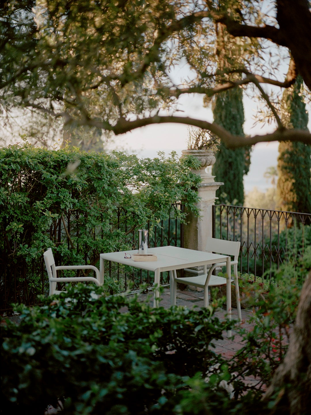 New Works May table and chair in light grrey in garden with book, glasses and pleat pitcher on it