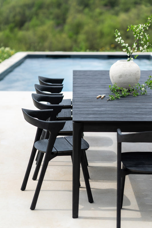 Ethnicraft bok outdoor chair in black teak next to the black outdoor table with plant on it