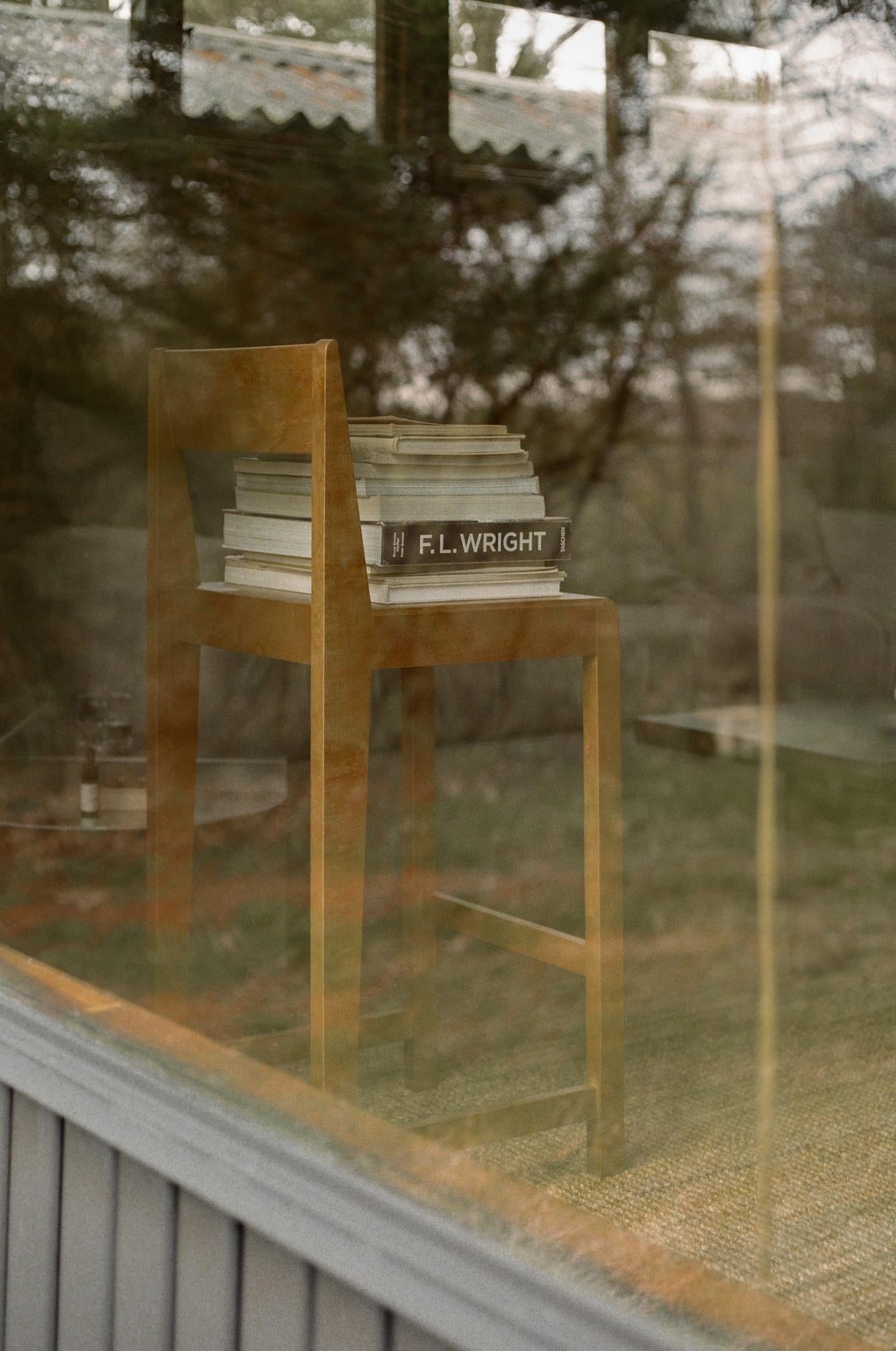 The Bar Chair 01 Warm Birch by FRAMA with books on it after a glass