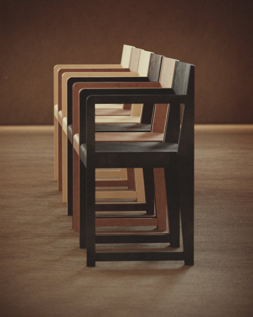 A row of the Armrest Chair 01 by FRAMA in different colours.