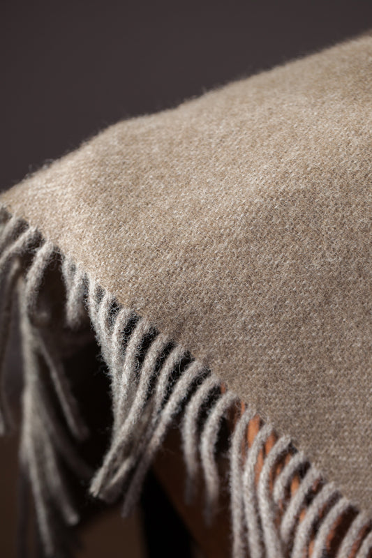 Close-up of the Earth Fawn Blanket, showcasing its woven texture and fine craftsmanship. Made from pure wool, a natural material known for its warmth and comfort.