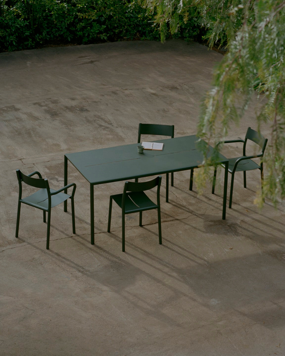 New works may table and chairs with and without armrests in dark green outside with tree