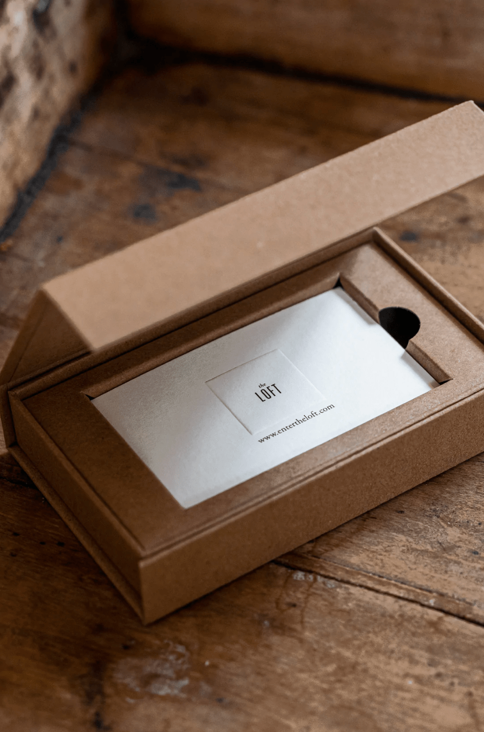 The Loft Gift Card design in brown cardboard box on wooden table