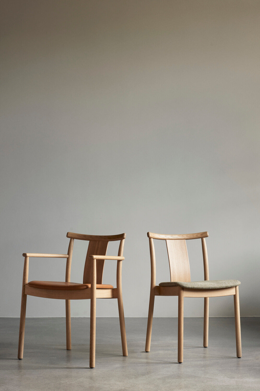 Two Merkur Dining Chairs with upholstery by Audo Copenhagen. The left chair has upholstery Dakar 0250 and the right chair has Hallingdal 65 200.