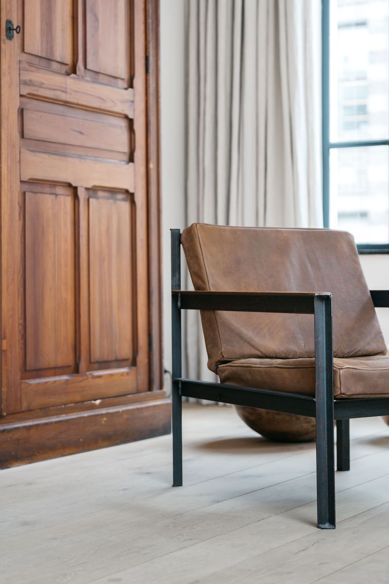 Armchair with metal frame and leather seating set in light interior.