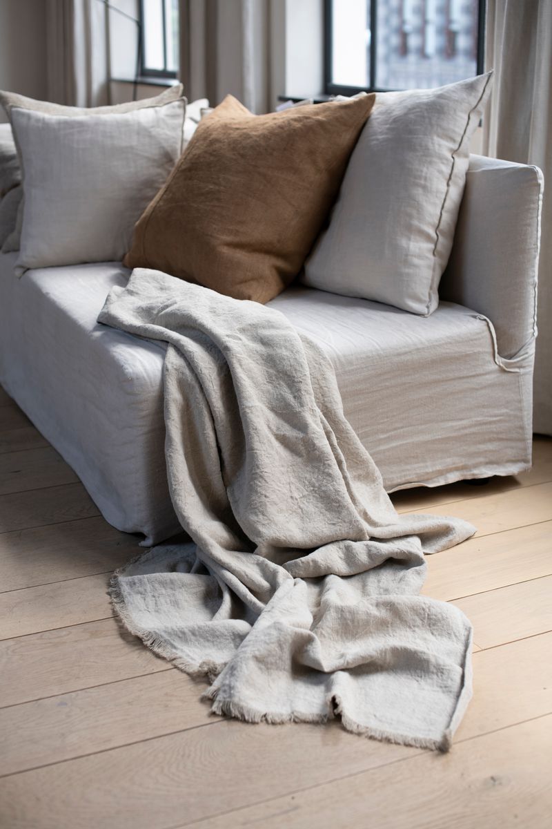 Linen Throw by Timeless Linen draped on couch in a light and neural interior at Enter The Loft.