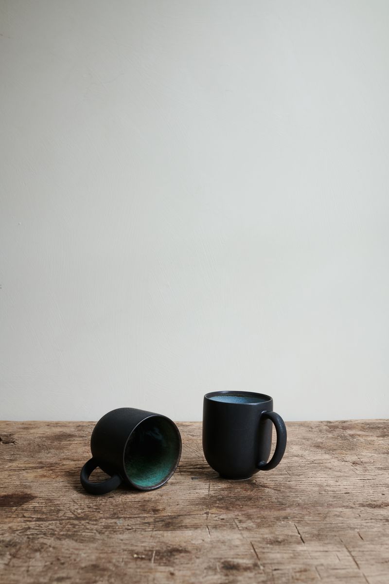 Two black Samoa Mugs with different inside colours.