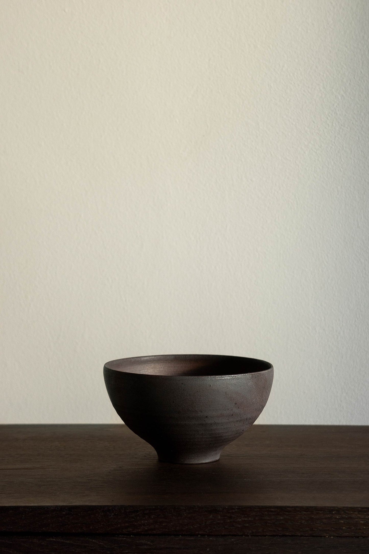 A black ceramic bowl from the brand Bonni Bonne set on a dark wooden table