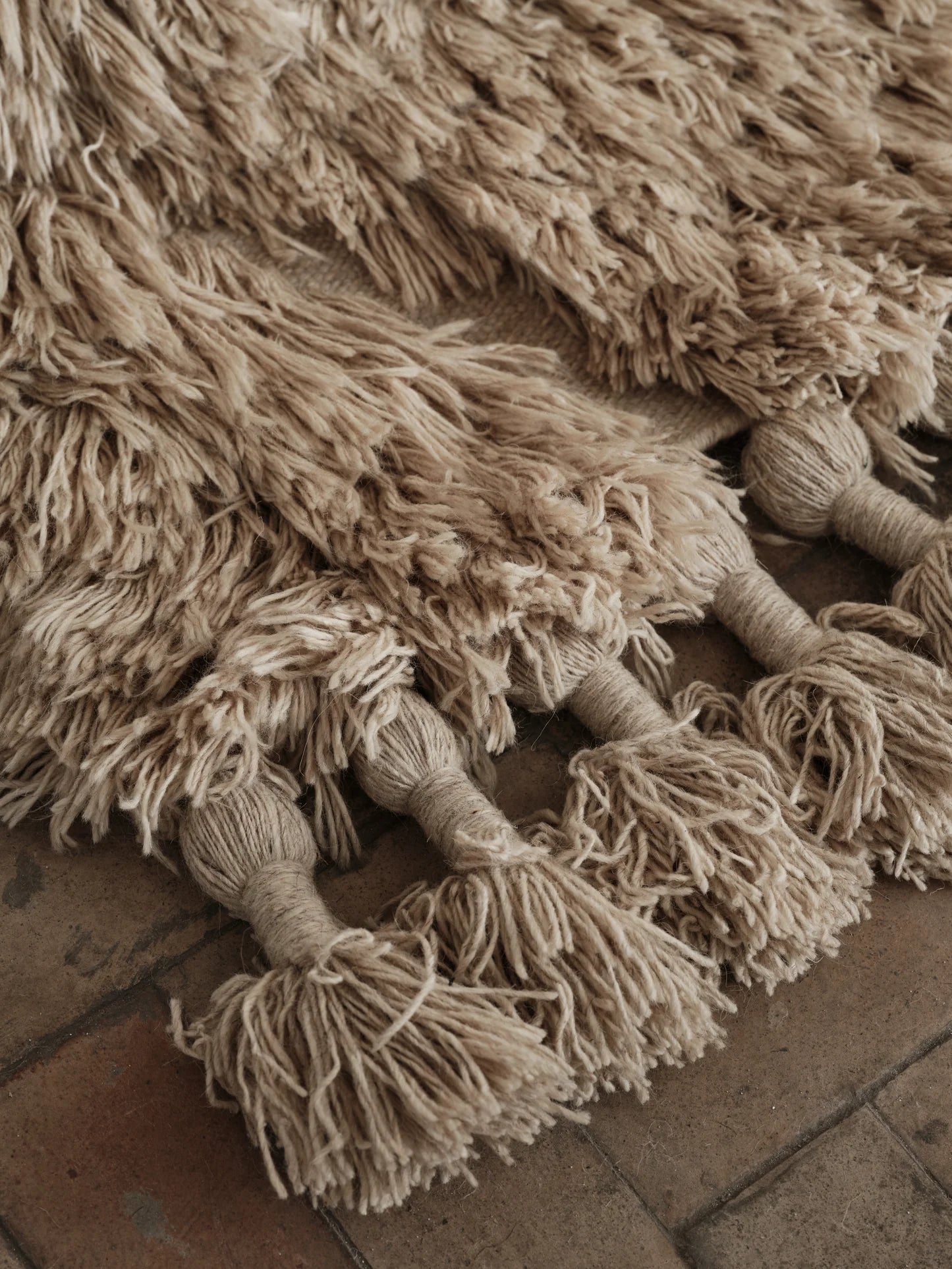 Details of a beige handwoven rug with tassels