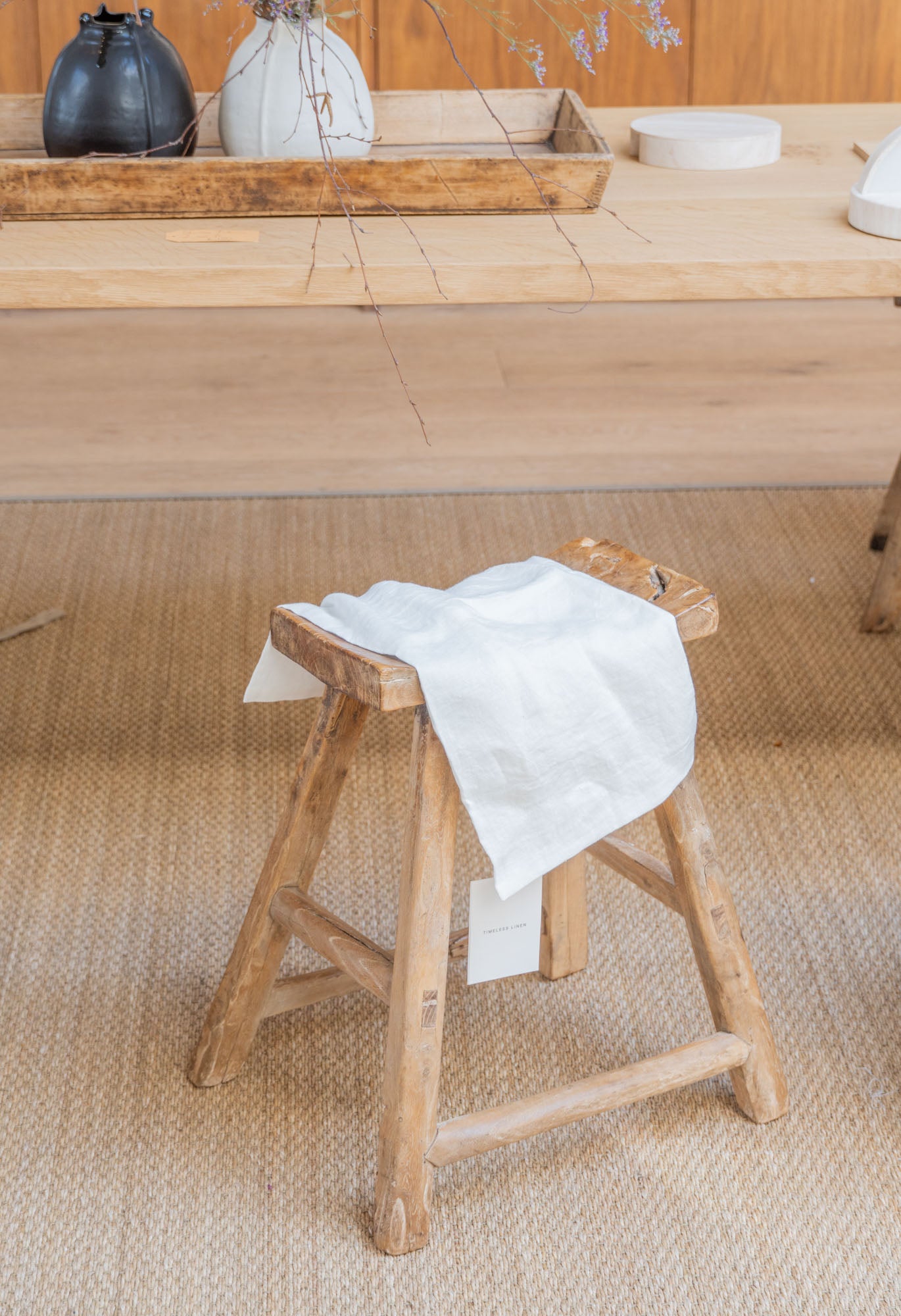 Timeless Linen Tea Towel hanging over wooden stool in neutral design interior.
