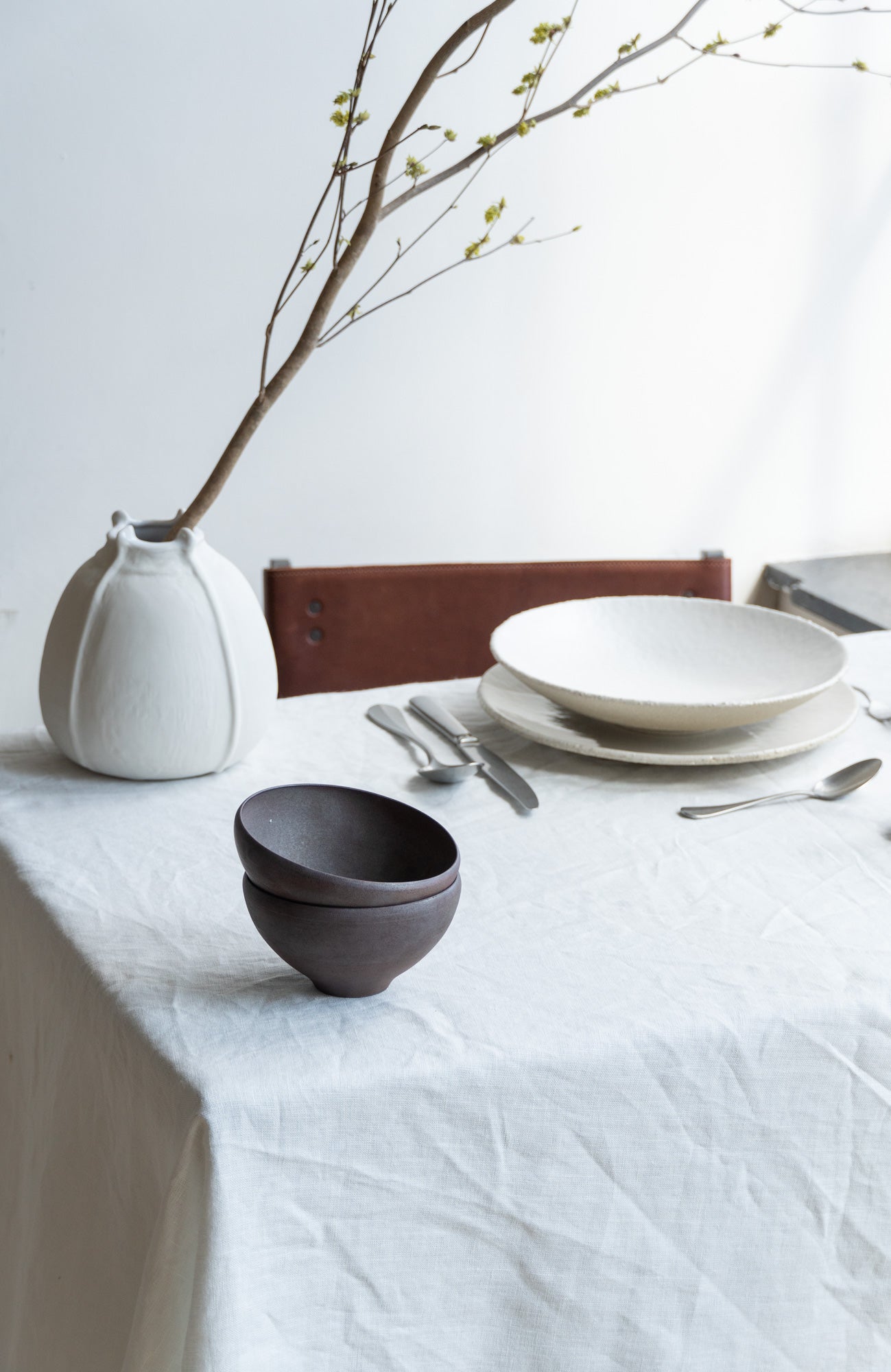black ceramic bowls by Bonni Bonne on a white linen table setting