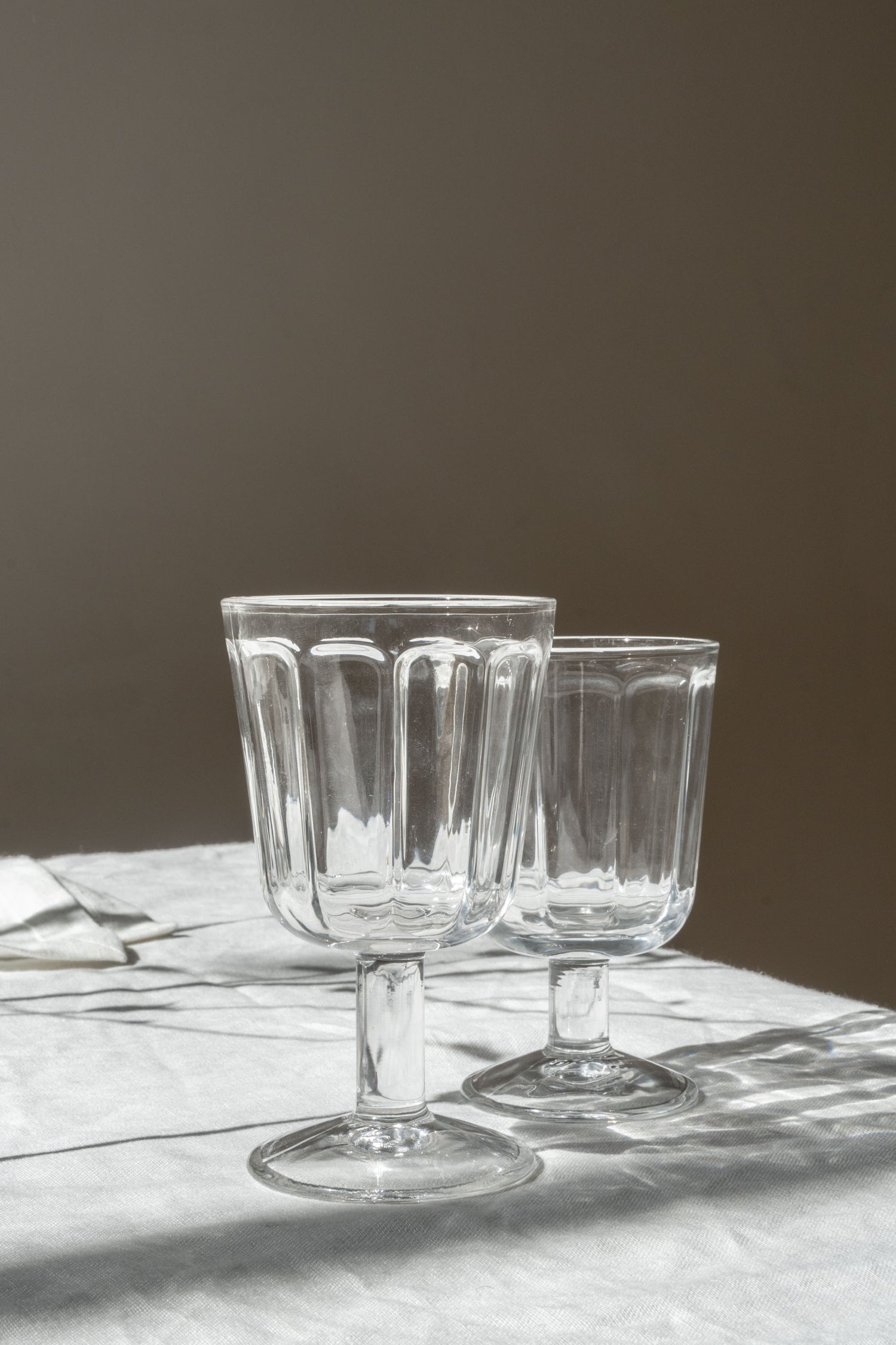 Two Surface Red Wine Glasses by Serax set on table with white linen.