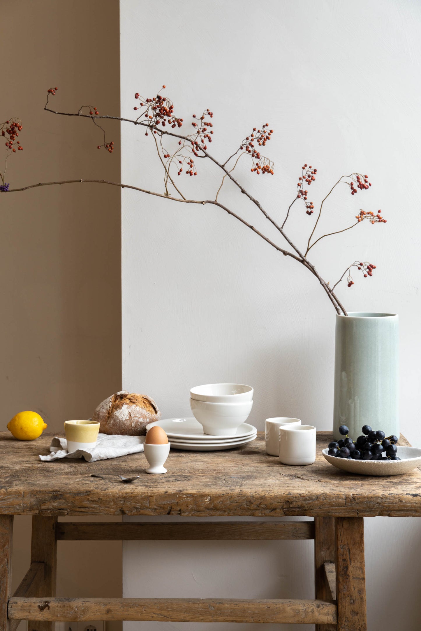 Breakfast table set with ceramic egg cup, plates and mugs.