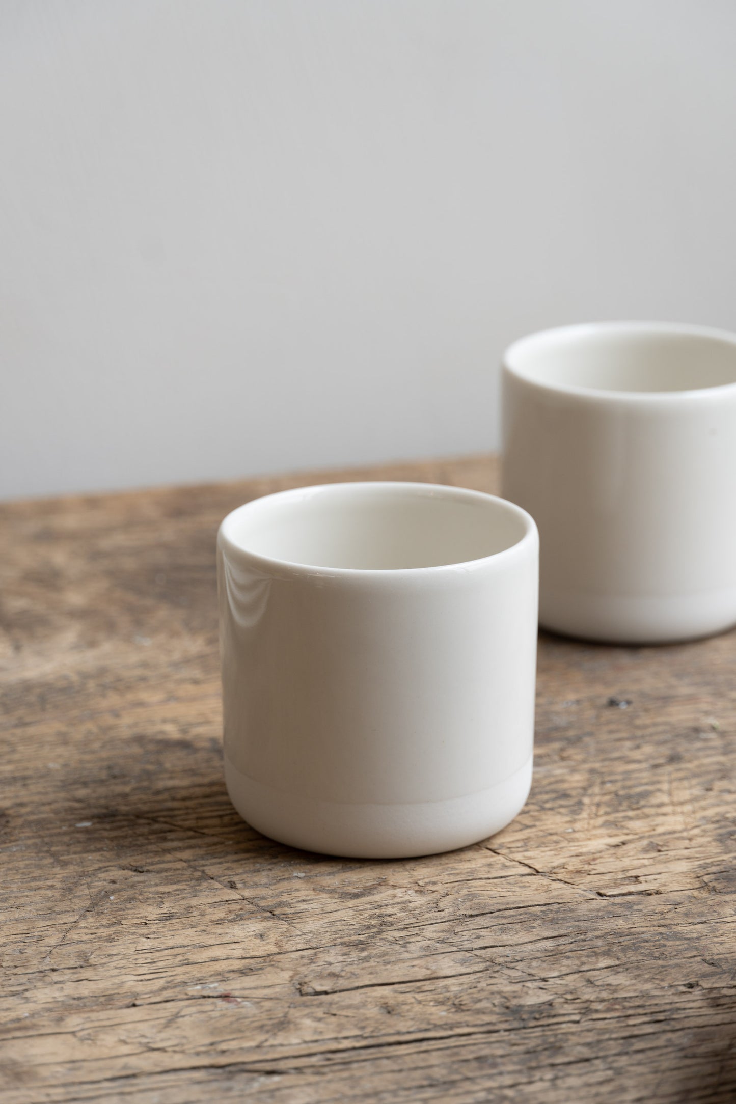 Two white Antibes Cups by Jars Ceramistes on wooden table.