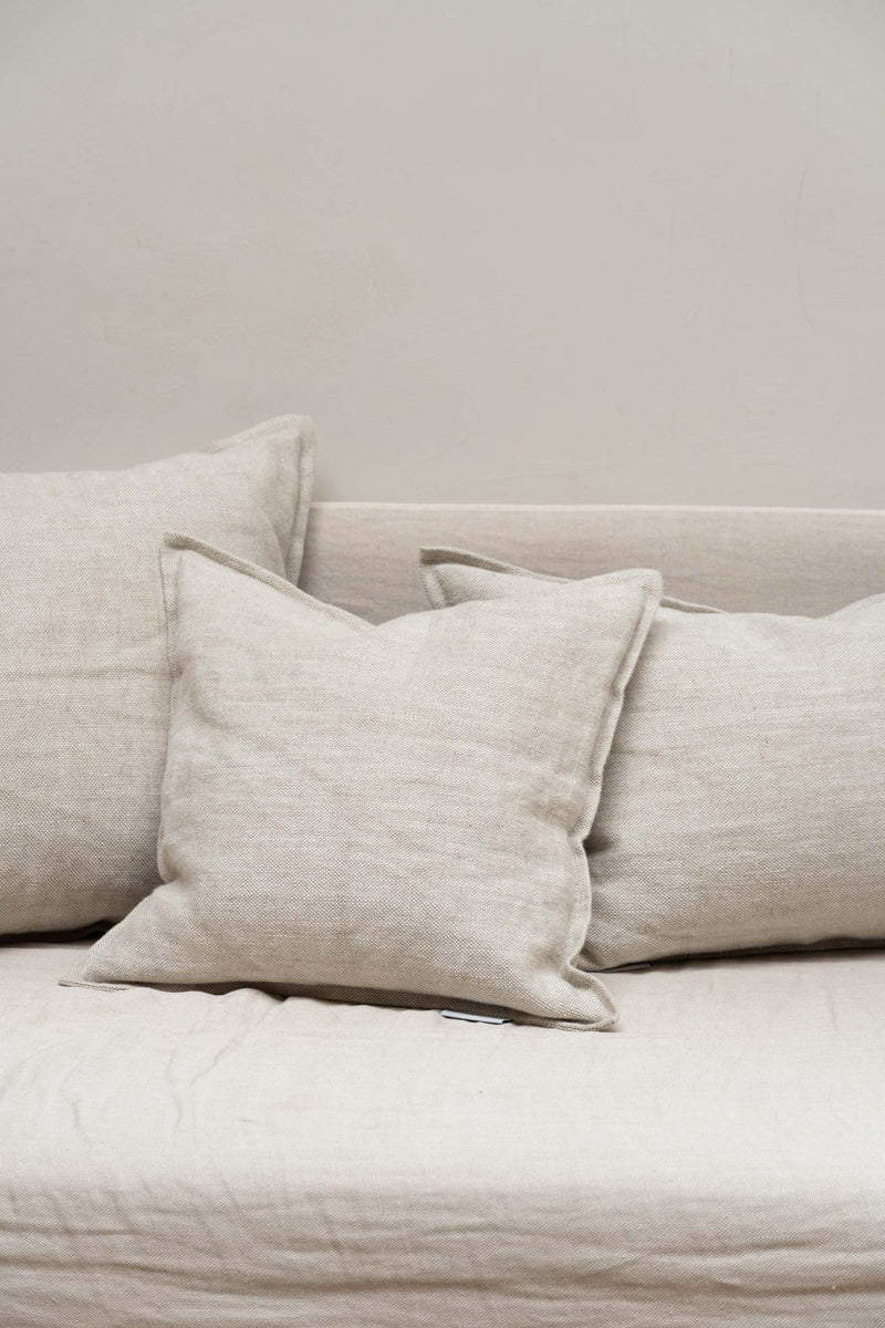 Three wheat-coloured Coarse Linen Cushions by Timeless Linen set on couch in neutral design interior at Enter The Loft.