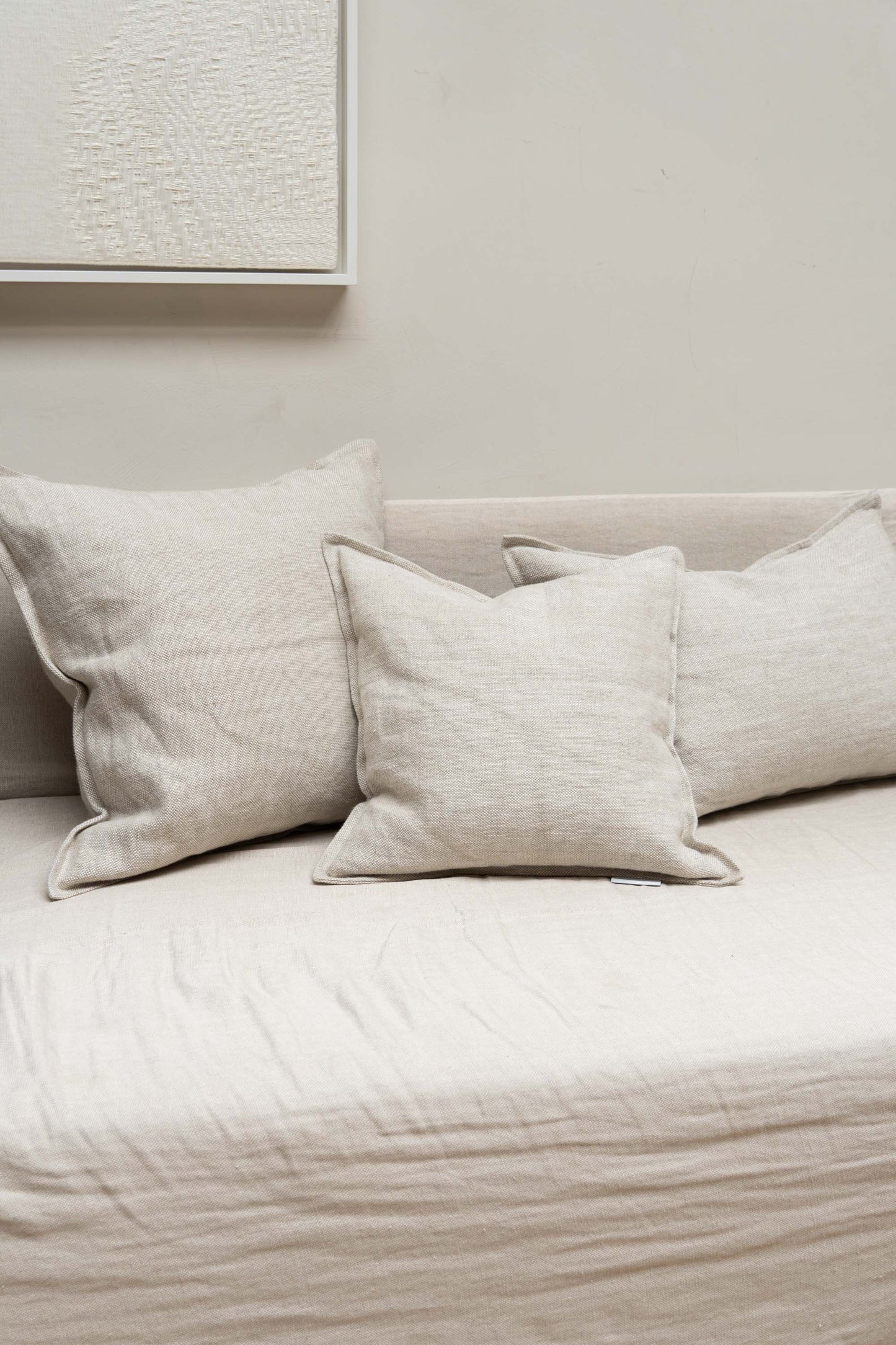 Three wheat-coloured cushions set on couch in neutral design interior.