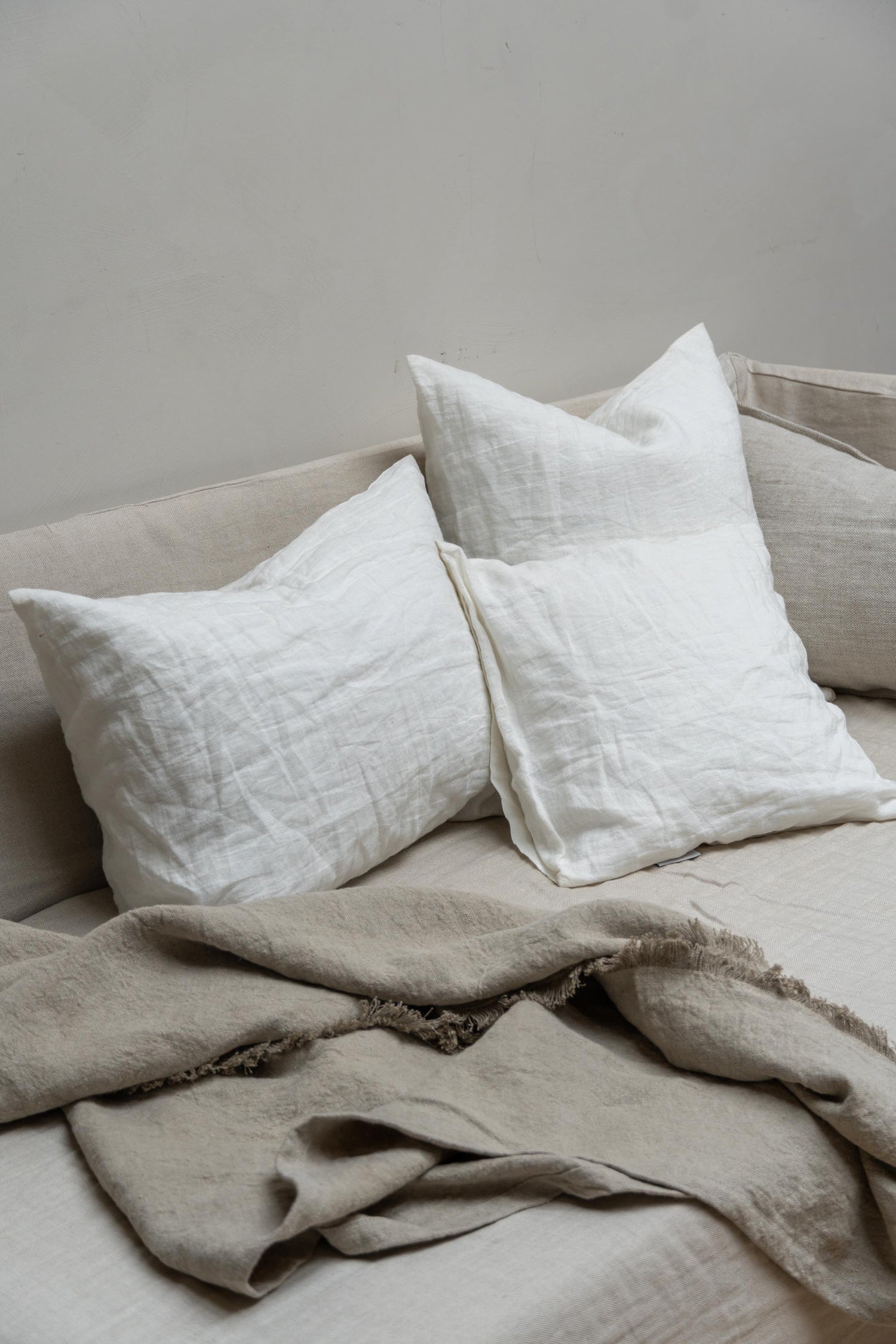 Linen Cushions by Timeless Linen in Off White set on couch with linen throw.