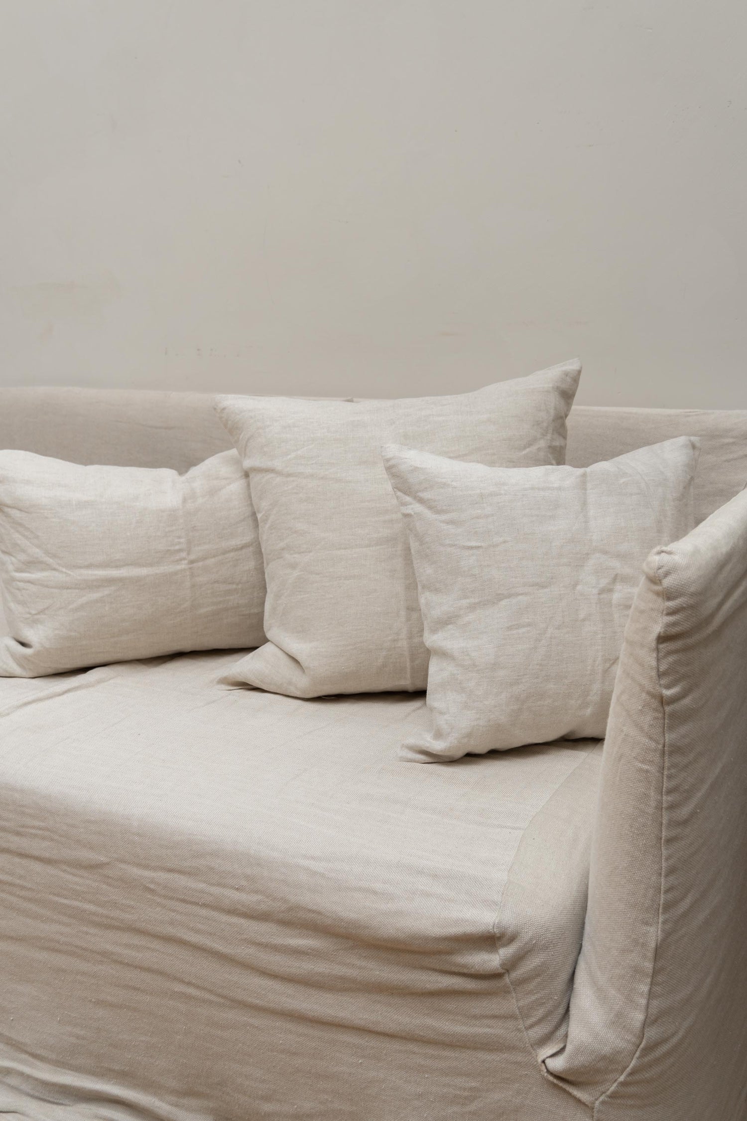 Oatmeal Linen Cushions by Timeless Linen set on couch in a light and neutral interior at Enter The Loft.