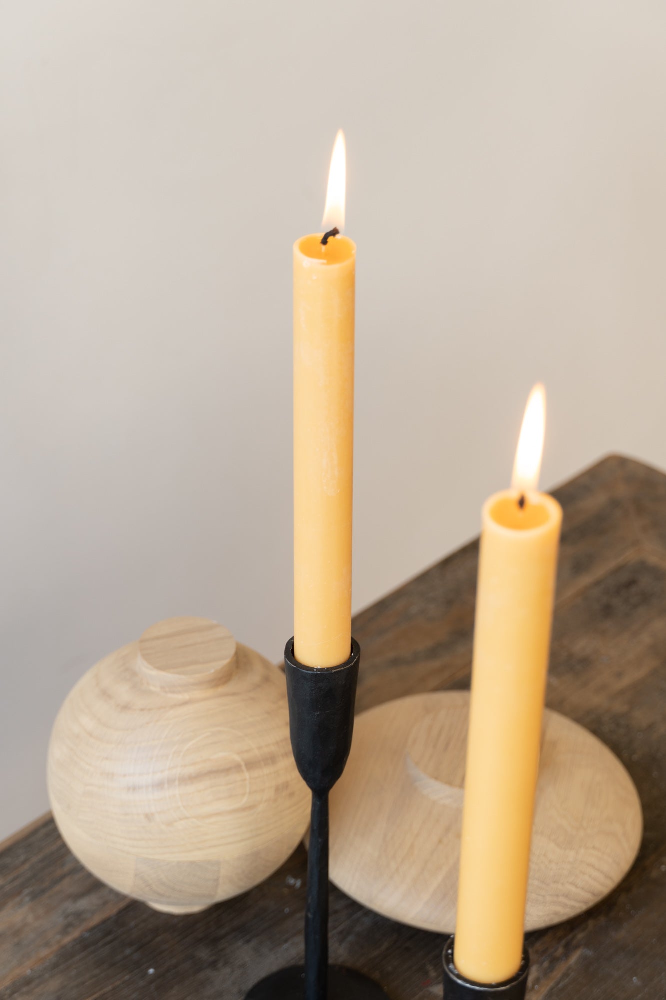 Two yellow dinner candles on wooden table.