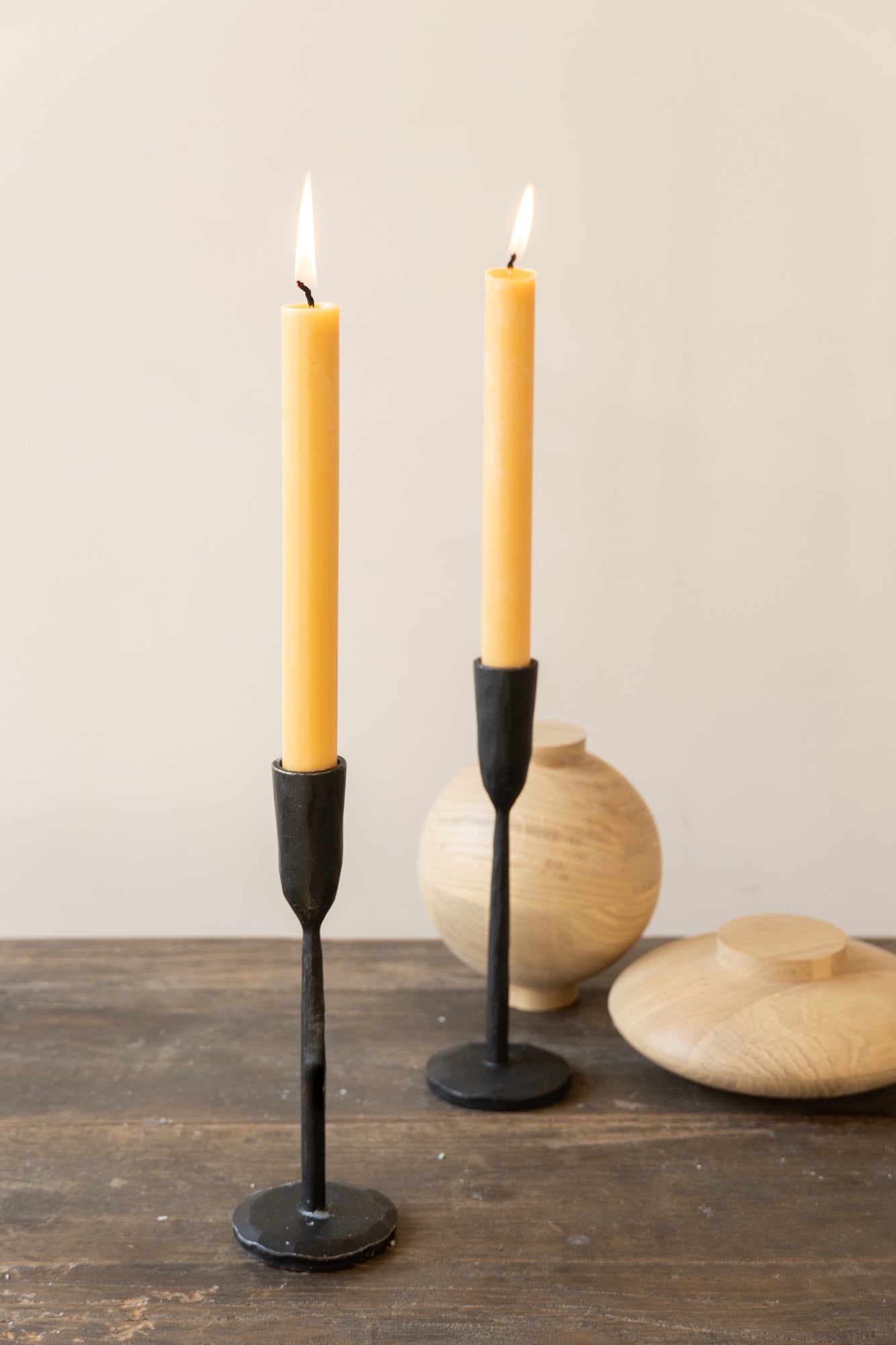 Two yellow dinner candles on wooden table.