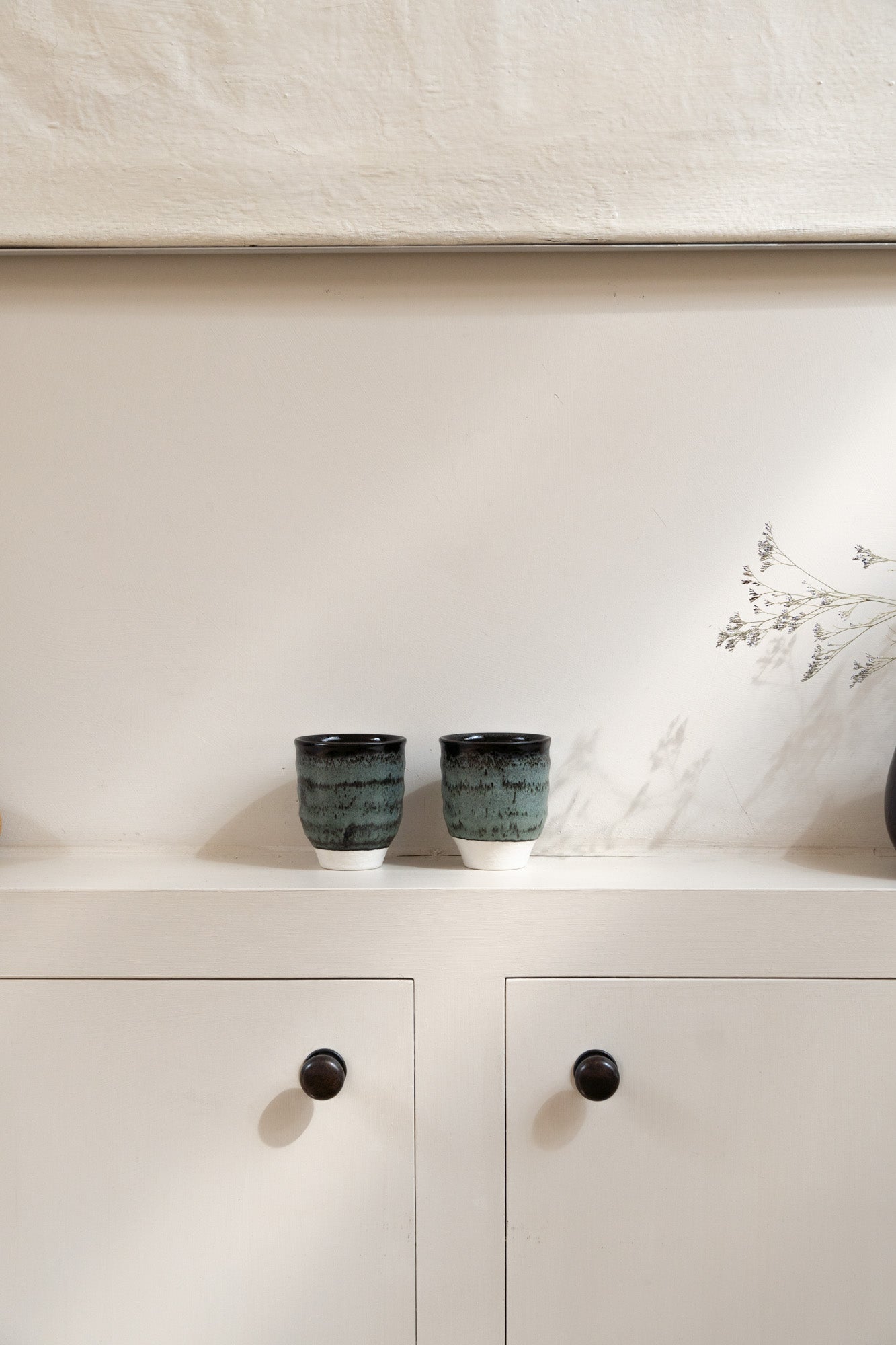 Two Dashi Tumbler in Charbon set on wall cabinet in light white and fresh interior.