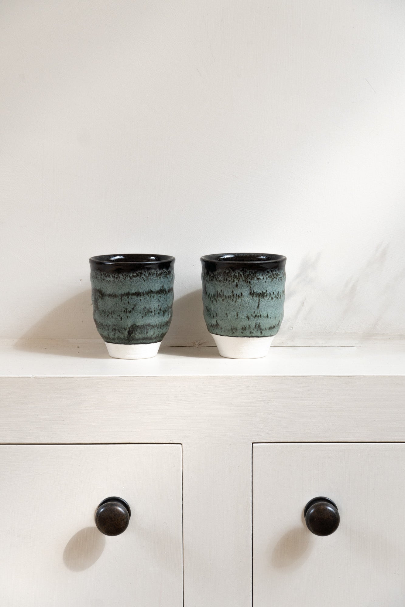 Two Dashi Tumbler in Charbon set on wall cabinet.