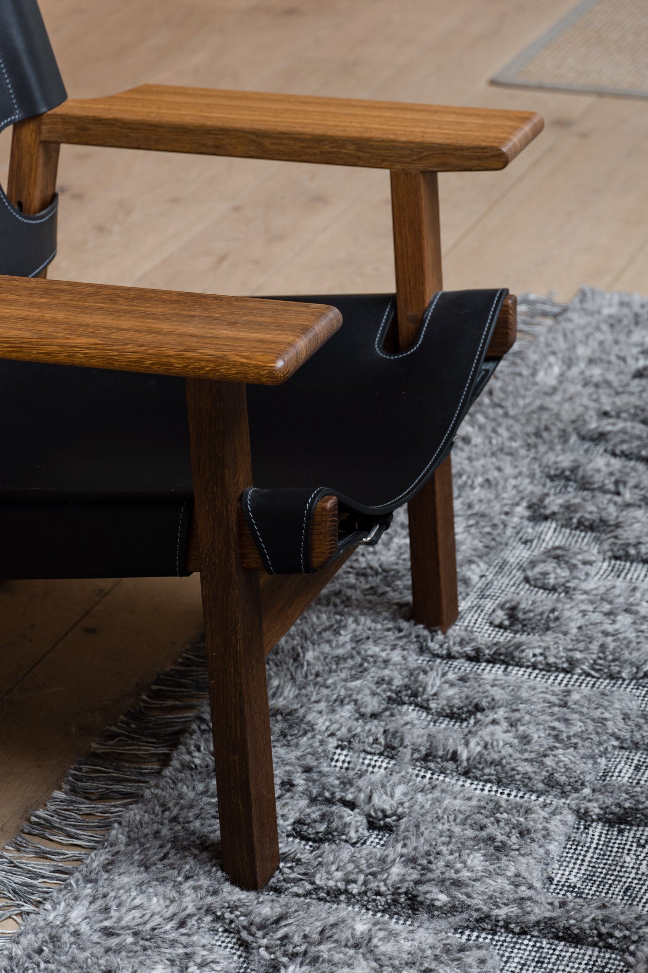 A wooden chair set on the PCB Rug by Zakaria Rugs.