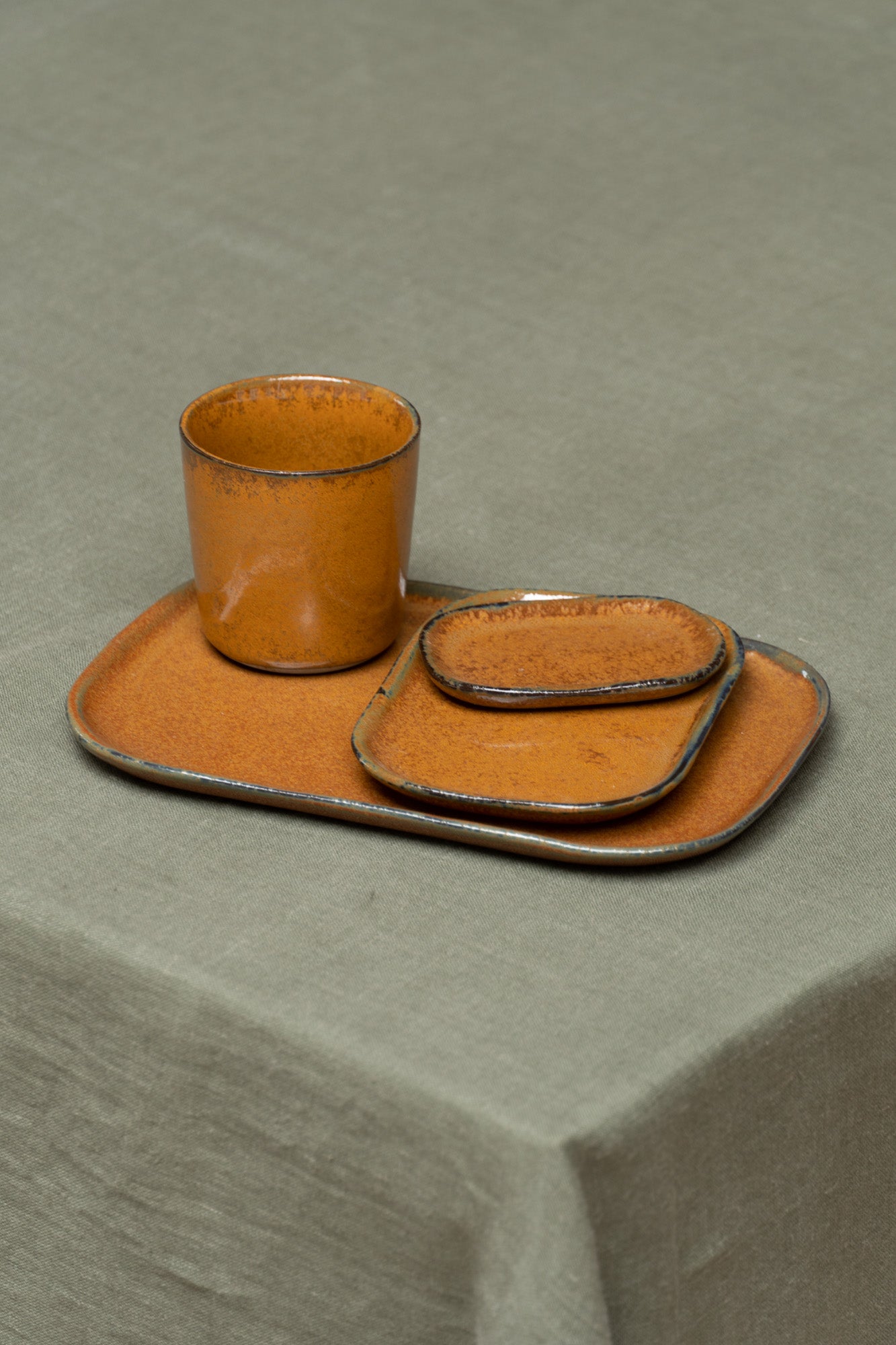 Kobe Plates in Brown by Serax at Enter The Loft. Set on table with matching Kobe cup.