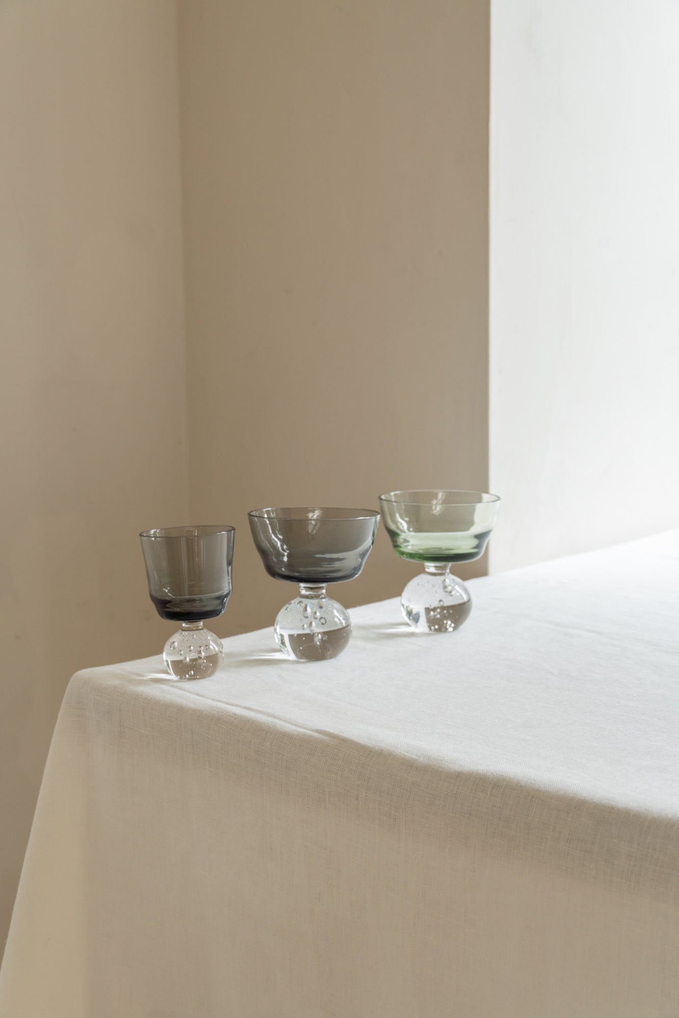 Serax Glass Smoky Grey Small with matching bigger glasses set on table.