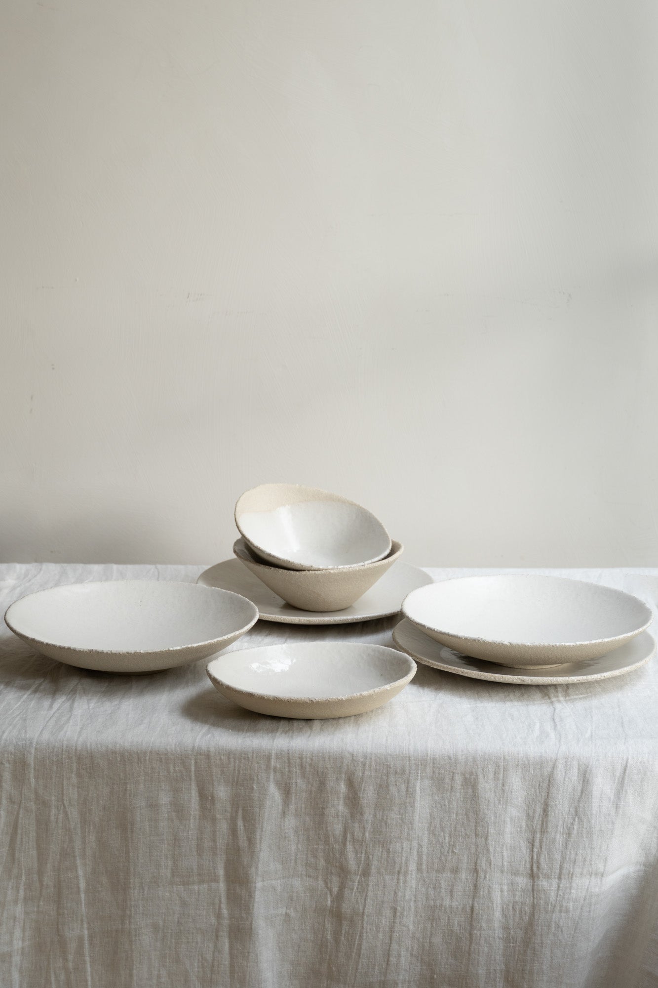 Table with white linen cloth and selection of Wabi Plates by Jars Ceramistes.