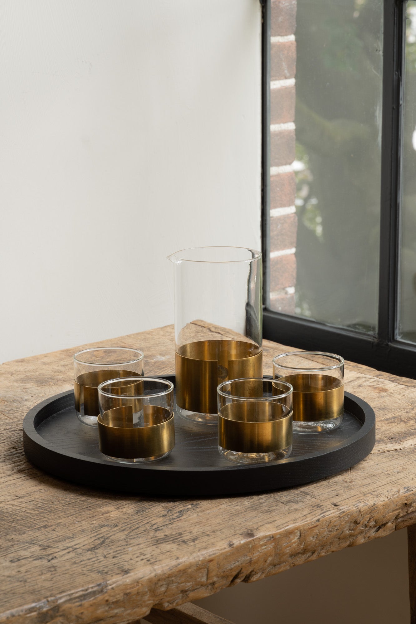 Copper Alchemy Chemistry Glass with matching carafe by Serax set on black wooden serving tray.