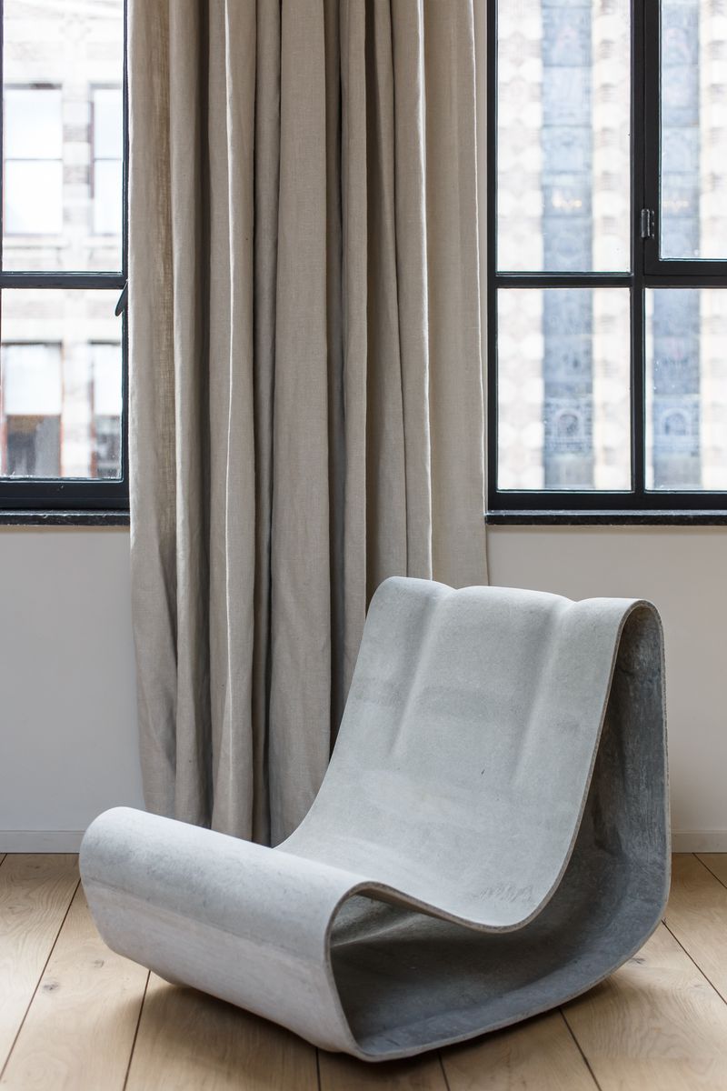 Loop Chair by Willy Guhl in front of big windows with curtains.