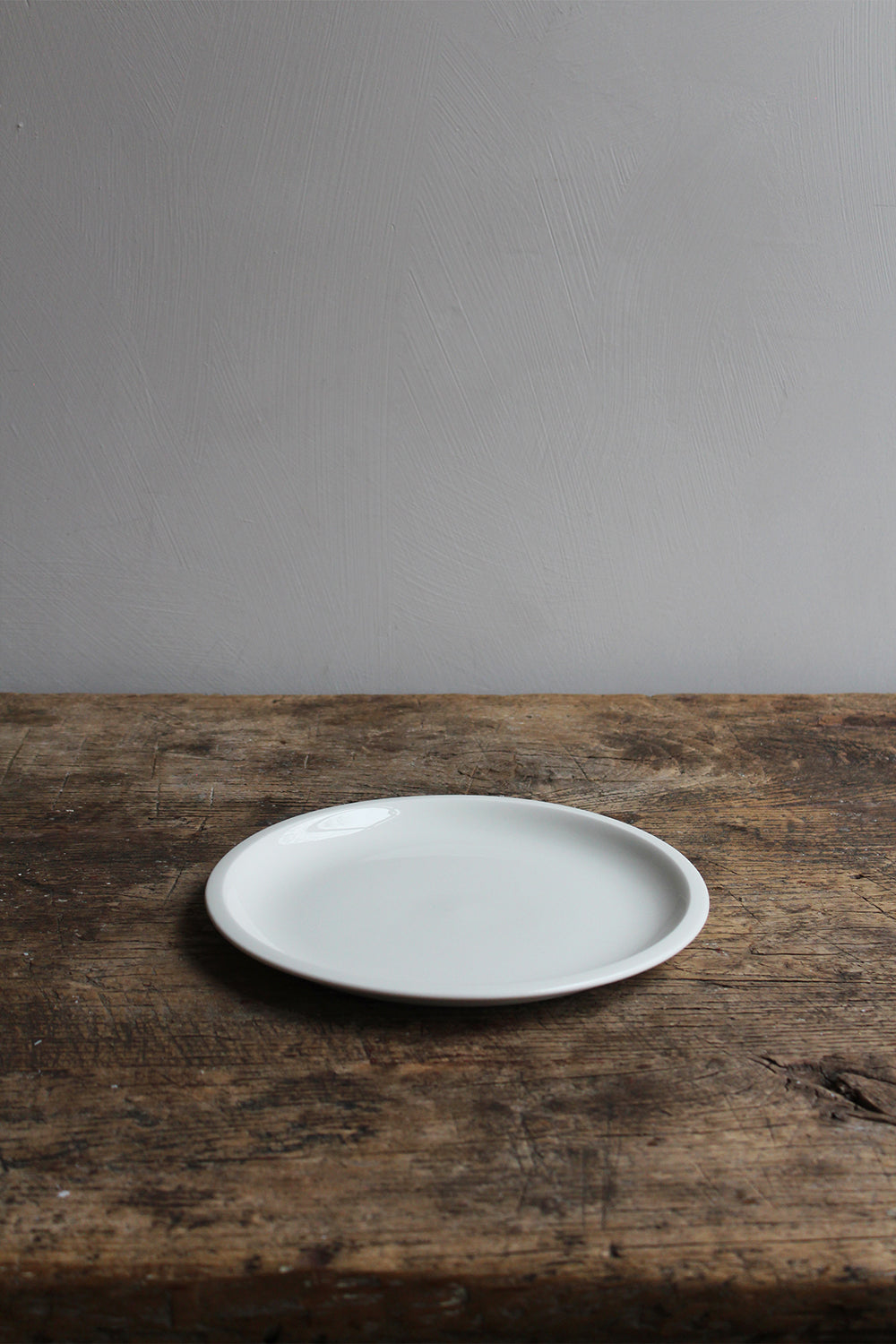 Single Antibes Plate White (24 cm) by Jars Ceramistes on wooden table.