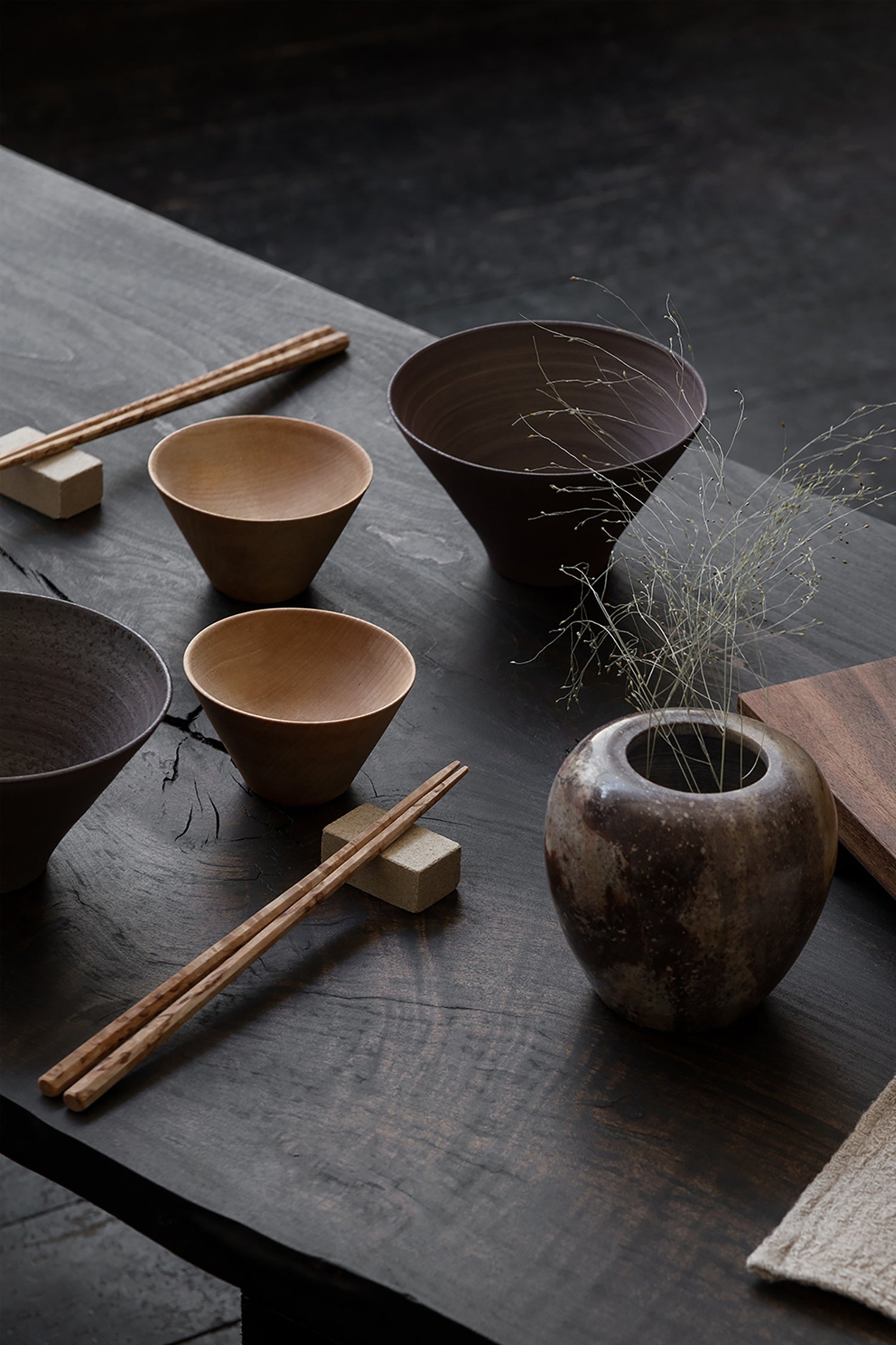 A dark Japanese styled table setting with chopsticks and Birch wooden Bowls
