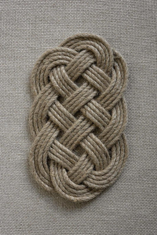 Braided trivet on neutral textile background
