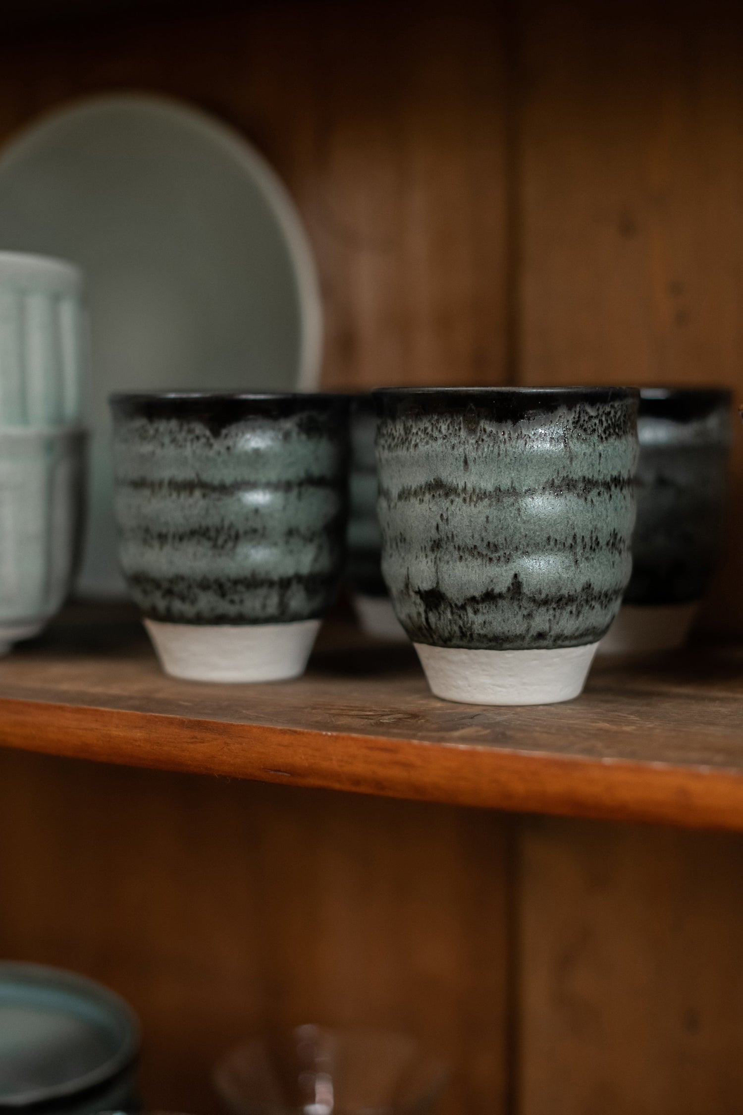 Ceramic mugs tumblers in a cupboard.