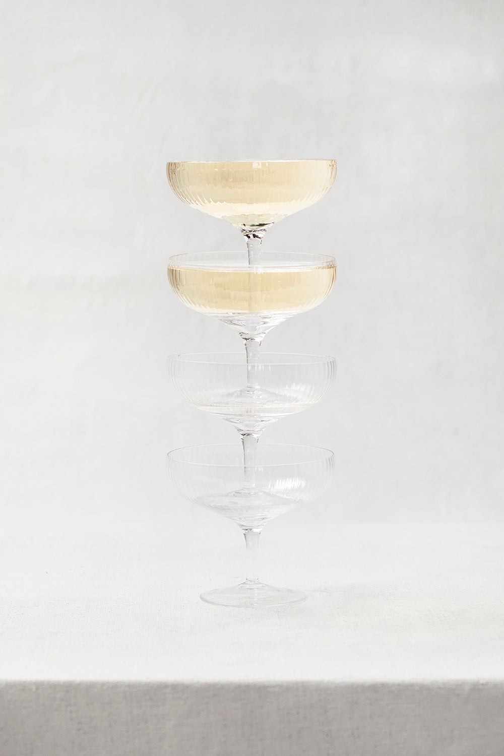 Serax Inku Champagne Coupe (set of 4) by Serax. Stacked full champagne glasses.