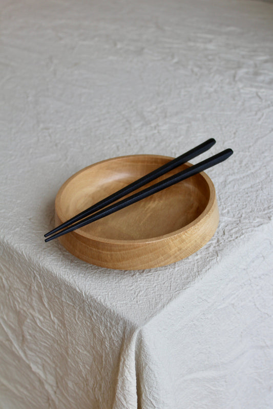 The asian style wooden bowl shown with black chopsticks. Weighing only 200 grams, it is easy to handle and adds a touch of natural beauty to your table setting.