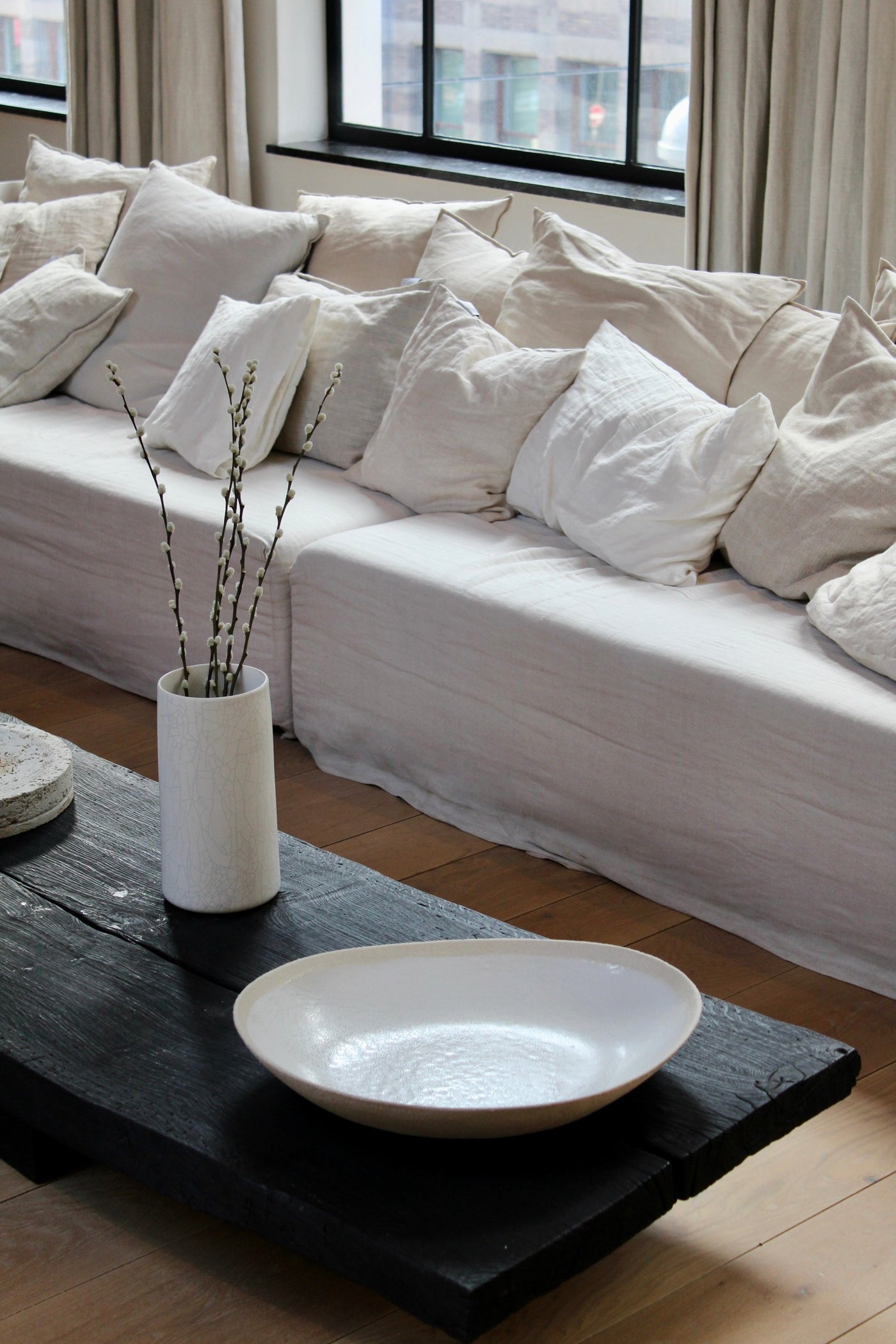 Wabi Serving Plate by Jars Ceramistes on black burned low coffee table in light interior at Enter The Loft.