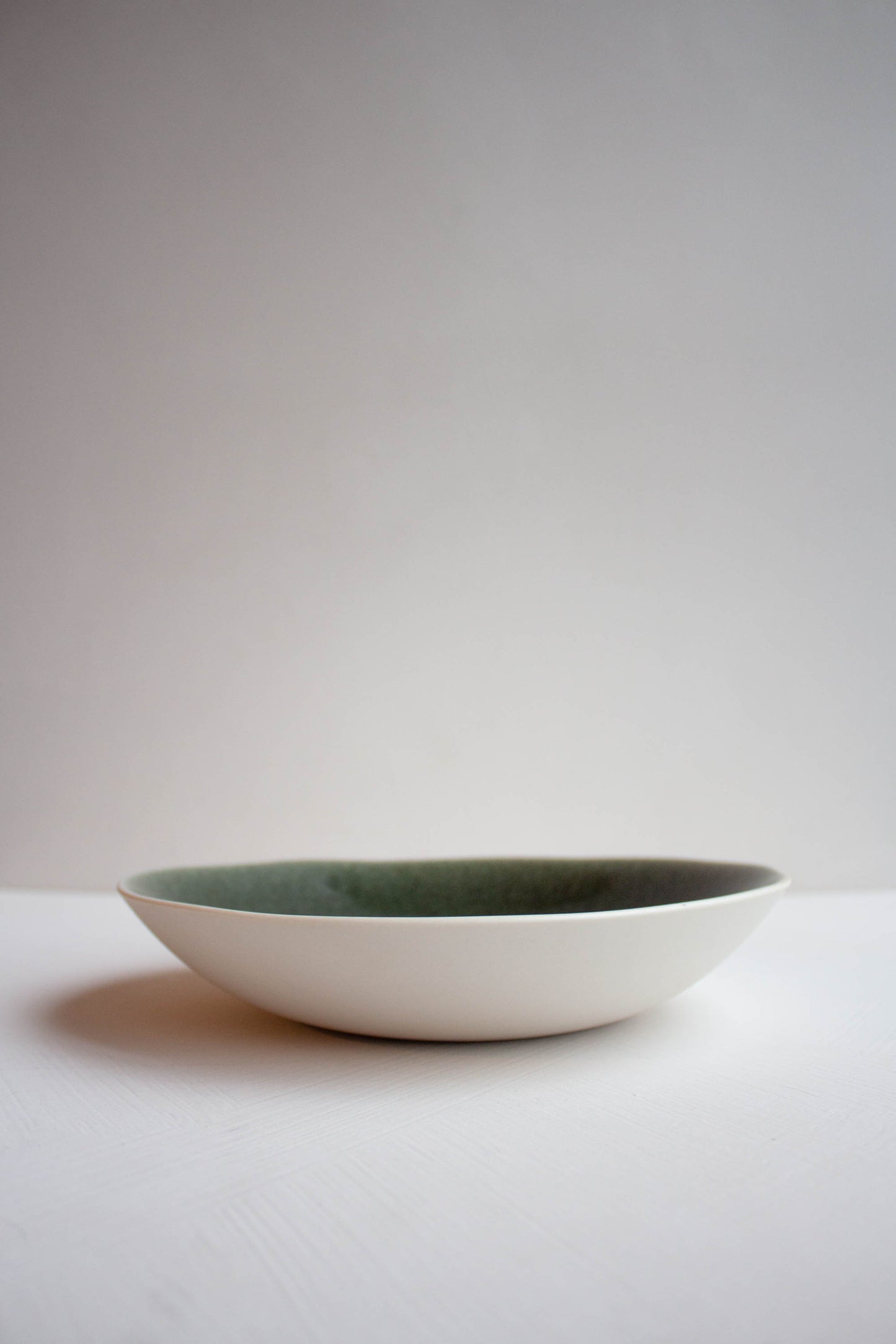 Side view of the Maguelone Deep Plate Forest Green by Jars Ceramistes.