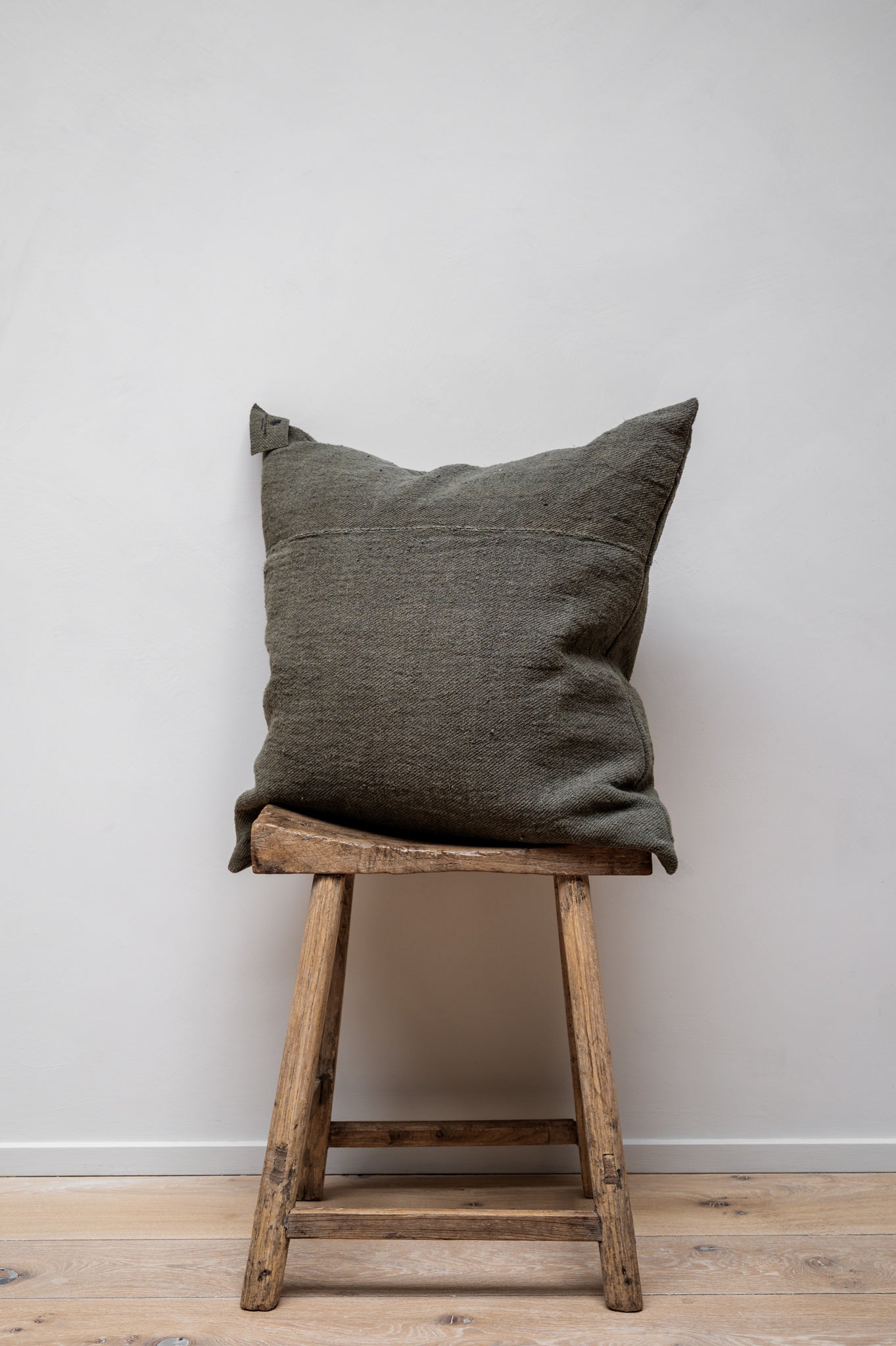 Chanvre Vintage - Olive Green Cushion by Isabelle Yamamoto set on a wooden stool.