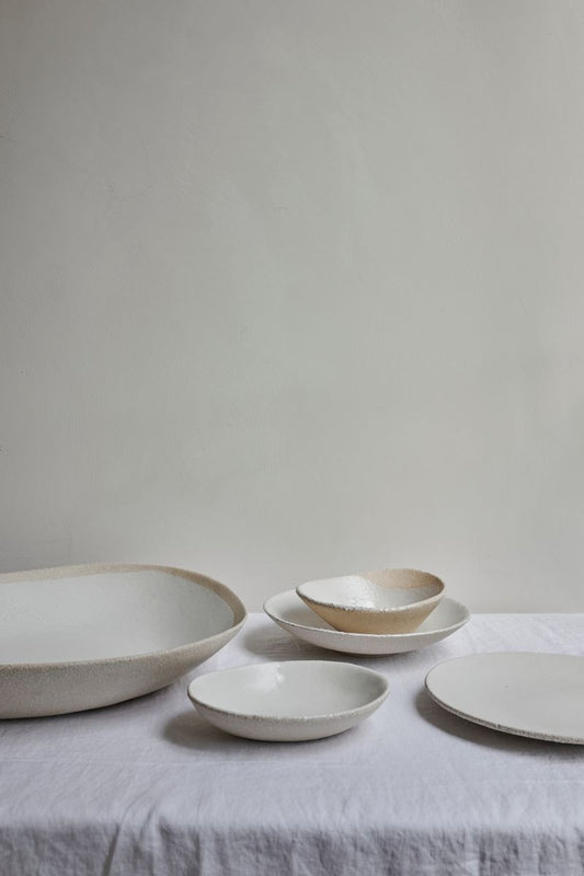 Table with white linen cloth and selection of Wabi Plates by Jars Ceramistes.