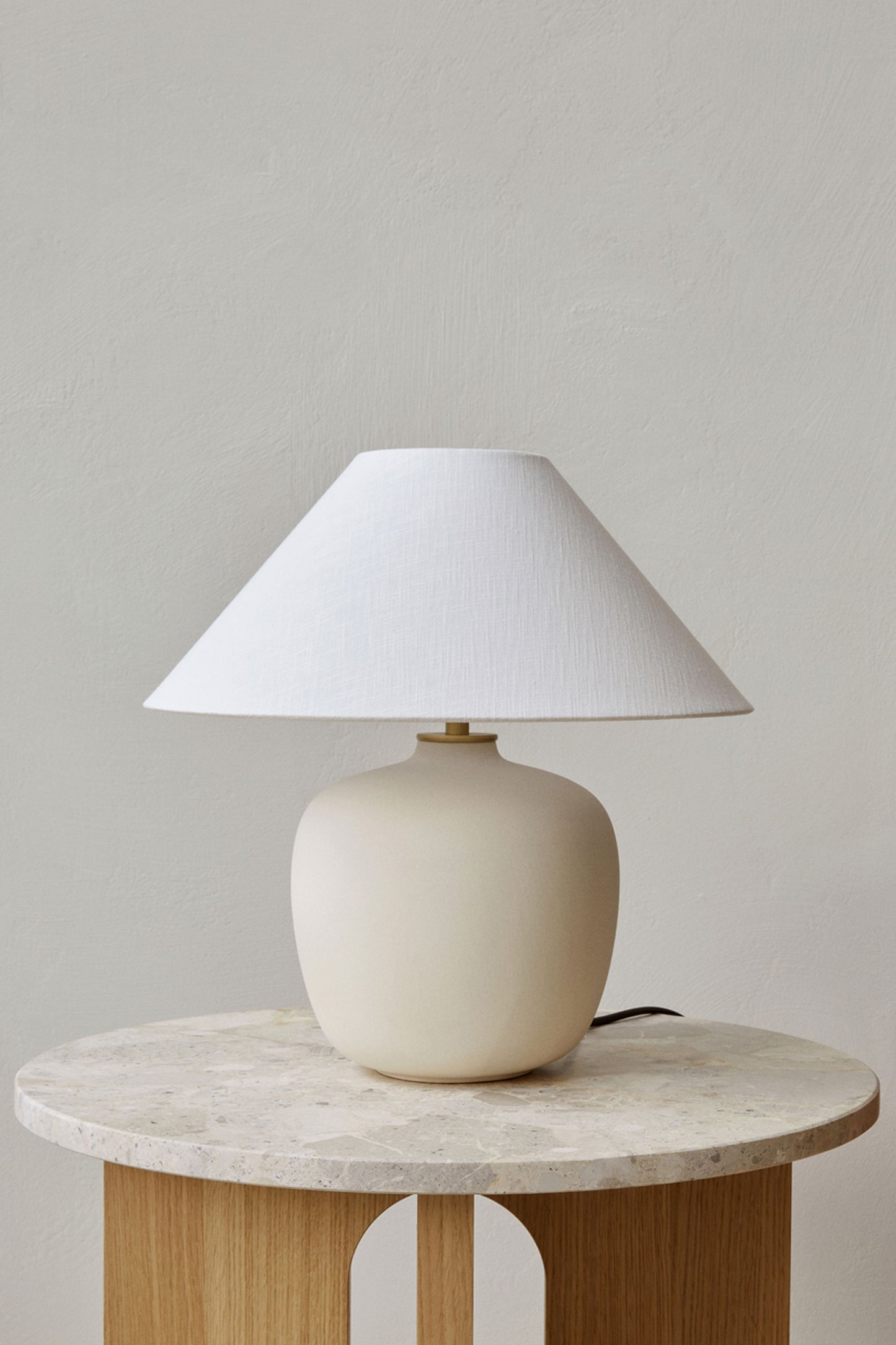 Torso Table Lamp Off White by Menu. Table lamp with ceramic base with handmade linen shade set on marble side table.