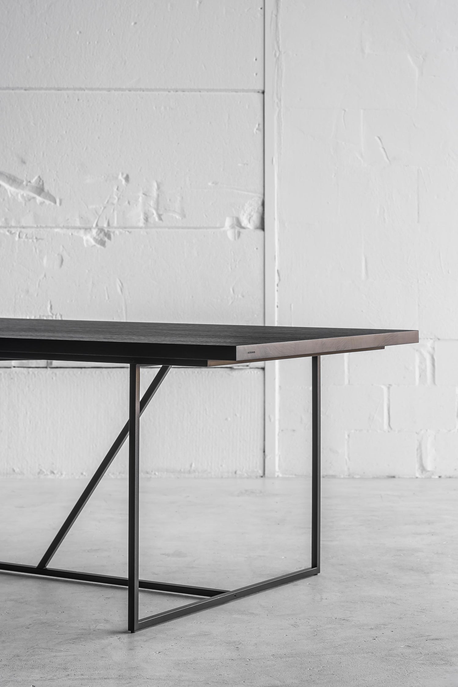 Long Mesa Nero Outdoor Table by Heerenhuis made from thick black Fraké wood with a steel base.