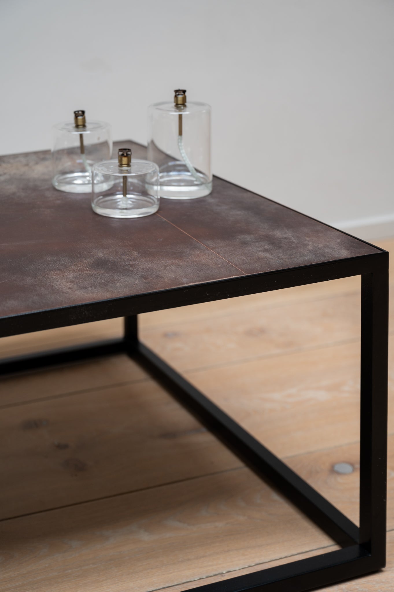 Close-up of the Mesa Nero Coffee Table by Heerenhuis with three sized of the Cyl Oil Lamp placed on it.