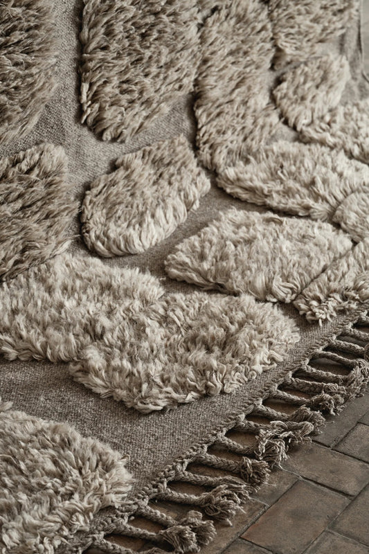 Detail shot of neutral handwoven rug with abstract pattern and small tassels