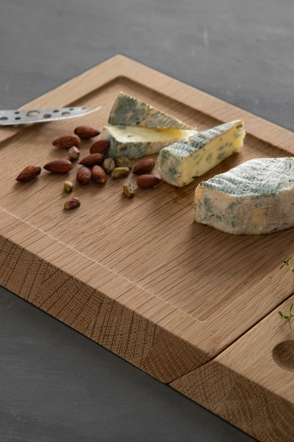 EKTA Living Cutting Board - a wooden cutting board with cheese and some nuts on it