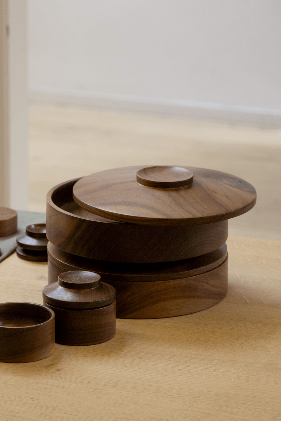 Repeat Stackable Cookie Jars with the lid slightly removed. The dark walnut wood creates a sense of warmth and the modular nature allows for creative arrangements.
