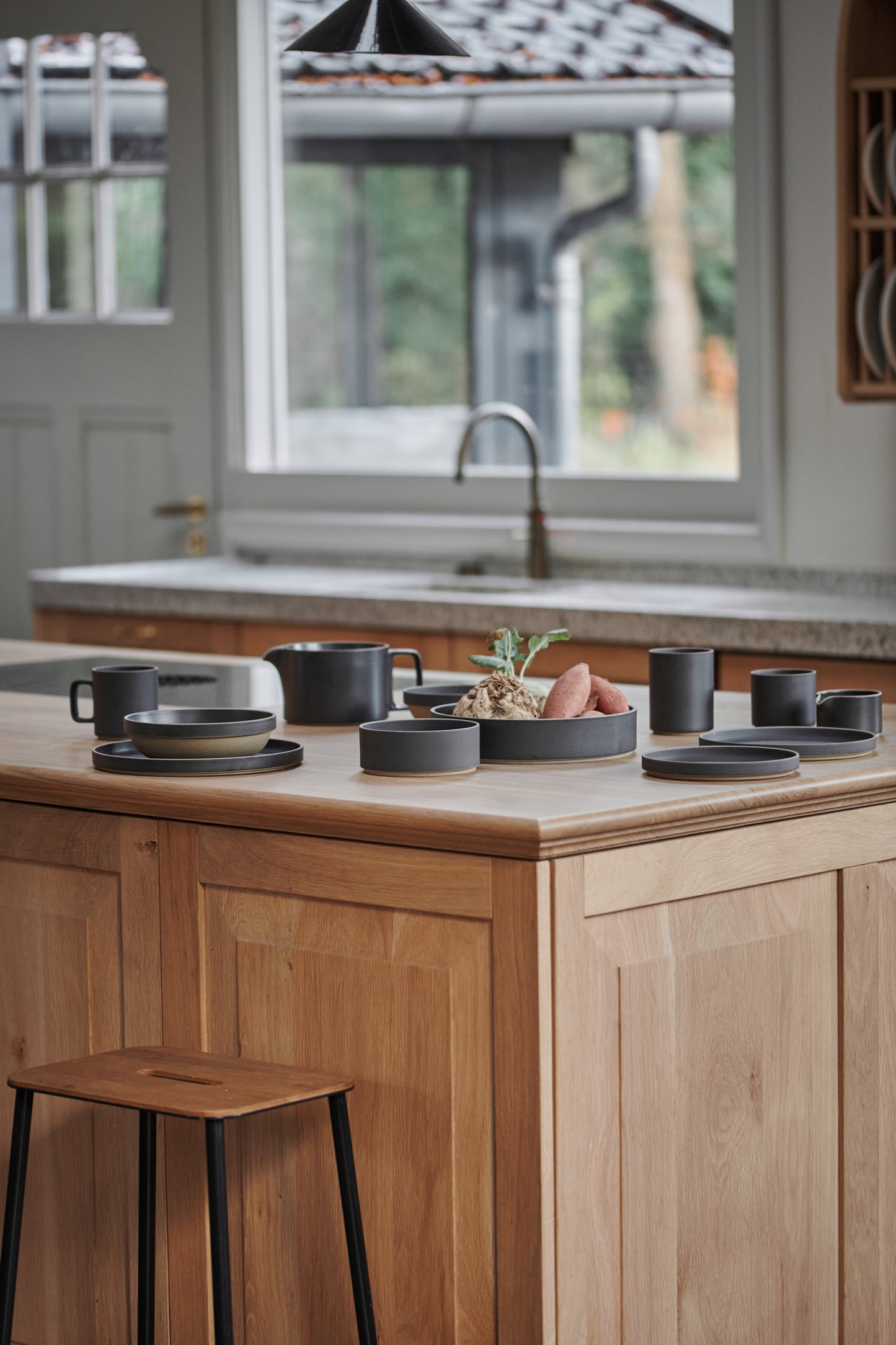 The Hasami Porcelain collection is displayed in a wooden panelled kitchen interior. Black ceramic Japanese-style design tableware.