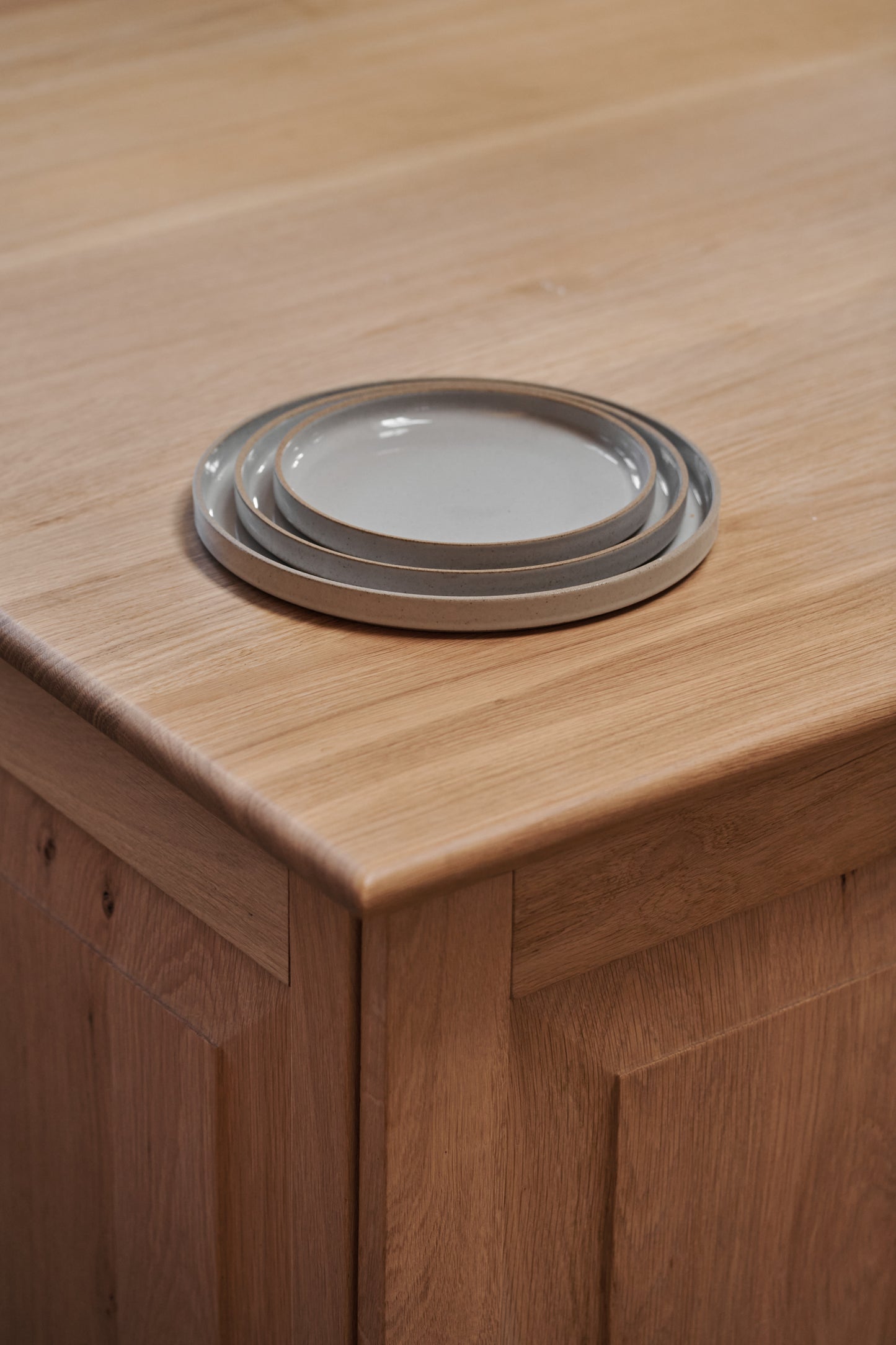 Grey Ceramic Stackable Plates by Hasami Porcelain displayed on wooden tabletop kitchen interior. Japanese-style design clay tableware.